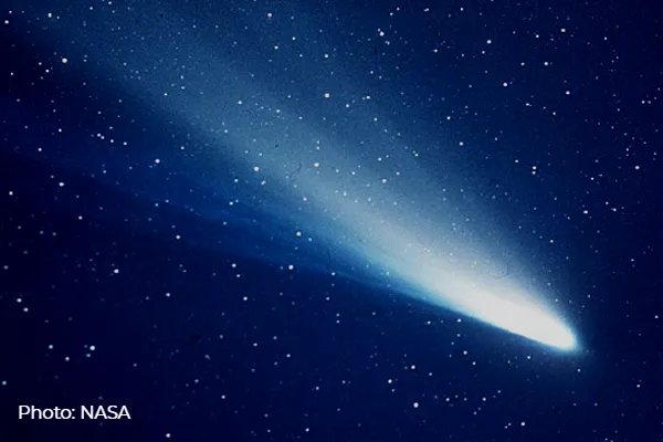 A photo of Halley’s Comet flaying across a blue starry sky with a long tail.